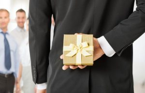 A businessman hiding a corporate gift behind their back as part of the company's effort to give the right corporate gifts.