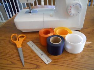 Materials needed to make holiday ribbon stockings include badge ribbons, scissors and a sewing machine.