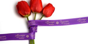 A custom ribbon roll with imprint for celebrating Mother's Day wrapped around tulips to demonstrate holiday product packaging.