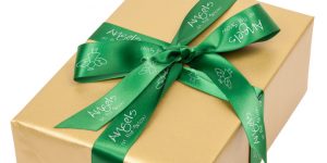 Custom green ribbon roll with imprinting to celebrate Christmas wrapped around a present.