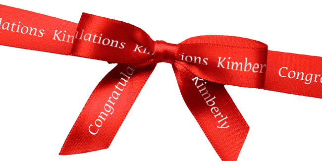 Metallic red imprinted ribbon roll tied into a bow for pretty packaging.