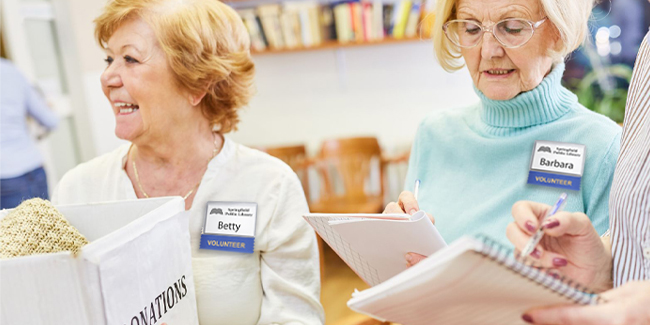 Women wearing badge holders and ribbons that help indicate they are volunteering at an activity.