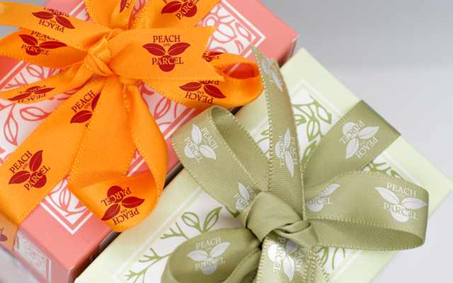 Custom imprinted ribbon rolls wrapped around boxes for product packaging.